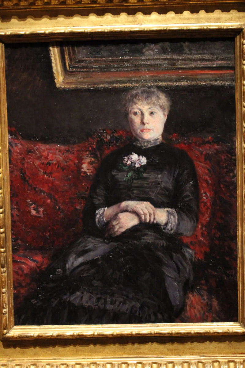 ผู้หญิงนั่งอยู่บนโซฟาที่มีดอกไม้สีแดง - Gustave Caillebotte